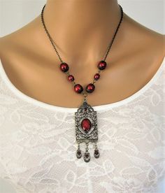 Red Victorian Style Necklace, handmade by Ralston Originals. This red pearl necklace is made with a large antique gold pendant, with red cabochon center, and 3 small charm dangles in antique gold with red crystals. The pendant is 3.5 inches long including the dangles, and 1 inch wide. The pendant is on antique gold brass chain, with dark red glass pearl beads, and antique gold bead caps. This Victorian red necklace is 18 inches long. This necklace is ready to send today, and it includes free shi Vintage Red Jewelry With Dangling Beads, Elegant Red Necklace With Vintage Charm, Antique Red Dangle Jewelry, Vintage Red Necklace With Dangling Beads, Red Vintage Necklace With Dangling Beads, Antique Red Handmade Necklaces, Antique Red Handmade Necklace, Ornate Handmade Red Necklace, Vintage Red Pendant Beaded Necklace