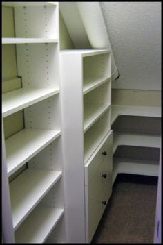 an empty closet with white shelving and shelves