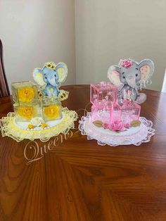 two small elephant figurines sitting on top of a wooden table