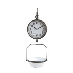 a clock hanging from the side of a wall with a bowl on it's stand