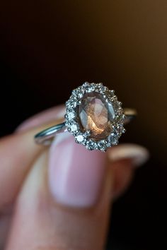 a woman's hand holding an engagement ring with a large brown diamond in it