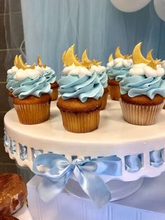 cupcakes with blue frosting and gold decorations on a white cake platter