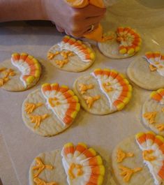 several cookies decorated like turkeys are on a baking sheet and someone is cutting them into small pieces