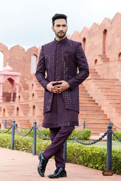 a man standing in front of some stairs wearing a purple suit and black shoes with his hands on his hips