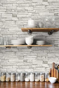 the shelves are full of dishes and bowls on the wooden table in front of the brick wall