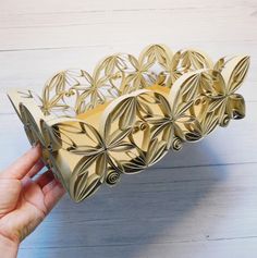 a hand is holding a decorative object made out of cardboard and paper with leaves on it