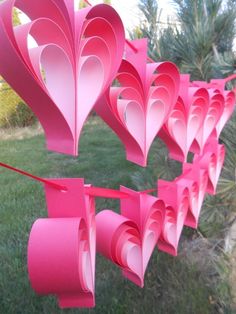 several paper hearts hanging from a line in the grass