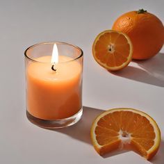 an orange sitting next to a candle on top of a white table with two halves cut in half