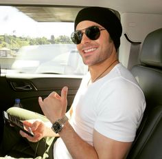 a man sitting in the back seat of a car wearing sunglasses and a beanie