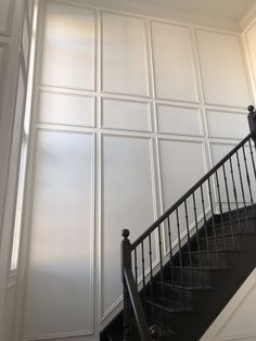 a staircase with white walls and black railing