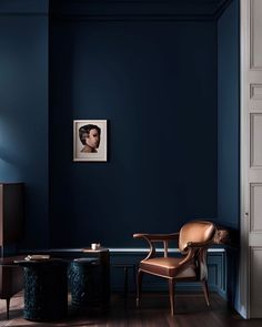 a living room with dark blue walls and a chair next to a table in the corner