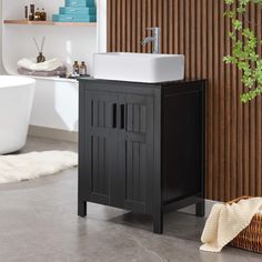 a white sink sitting next to a black cabinet and bathtub in a room with wooden slats