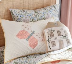 a quilted bed with two pillows and a house pillow on it's side