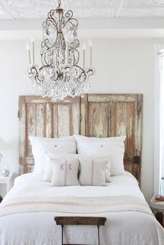 a bedroom with a bed, chandelier and pillows