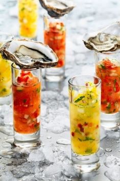 several glasses filled with different types of food and drink on ice covered table next to each other