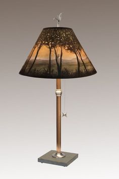 a lamp that is sitting on top of a wooden stand with a tree in the background