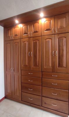 a large wooden cabinet with many drawers and lights on it's sides, in a room that has white tile flooring