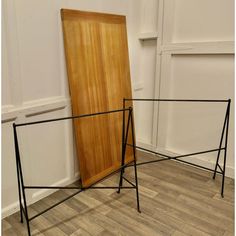 a wooden door sitting next to a metal frame on top of a hard wood floor