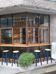 an outside view of a restaurant with stools and tables in front of the window