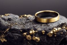 a gold wedding ring sitting on top of a rock