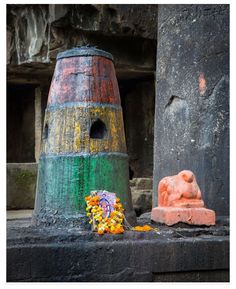 an old barrel with flowers on the ground next to it and a small statue in front of it