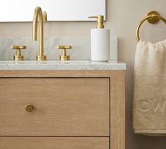 a bathroom sink with two gold faucets and a towel hanging on the wall