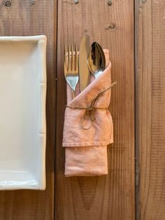 a white plate and silverware on top of a wooden table next to a napkin