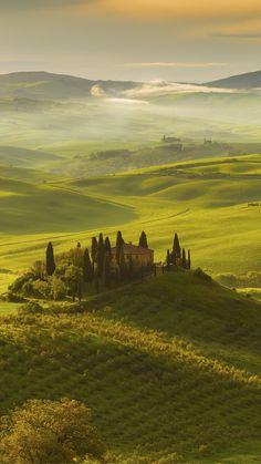 the rolling hills are covered with green grass and trees, as well as an old building