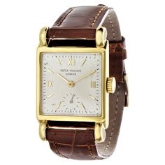 Introduction: Patek Philippe 2435J rectangular shaped 18K yellow gold watch, made in 1948. The watch measures 25 x 40mm. The case design is with a flared case with large half round lugs, silver dial with raised gold roman numerals and indices. The watch is fitted with a 10"200 caliber movement # 952267, case# 652635. The watch is extremely well preserved with its strong hallmarks deep and only slightly polished case. The watch is further fitted with an brown alligator strap. Date and Paperwork: Rectangular Watch, Case Design, Square Watch, Patek Philippe, Roman Numerals, Silver Band, Gold Watch, Alligator, Leather Watch