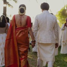 a man and woman holding hands walking down a path with other people in the background