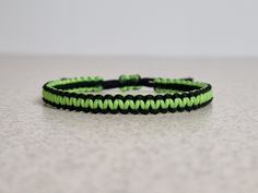 a green and black string bracelet on a table