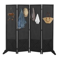 a room divider with four pieces of clothing hanging on the hooks and two hats