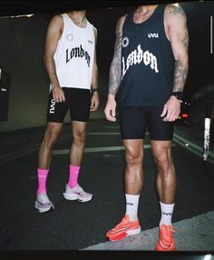 two men standing next to each other in shorts and socks, one with pink socks