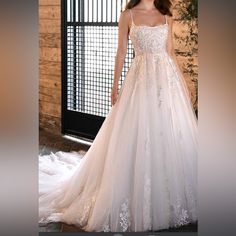 a woman in a white wedding dress standing next to a window