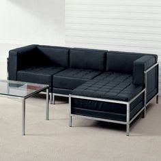 a black couch sitting next to a glass table on top of a carpeted floor