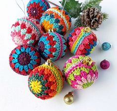 crocheted ornaments are arranged on a white surface next to pine cones and greenery