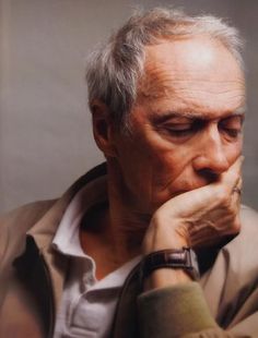 black and white photograph of an older man with his hands on his chin looking to the side