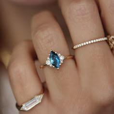 a woman's hand with three different rings and one ring has a blue topazte