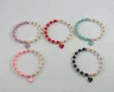 Stunning stretch faux pearl bracelets! This half and half design makes them so gorgeous! Created with 6mm pearls, heart charms and very strong and durable stretchy cord. Main colors available for the beads and heart charms are red, light purple, light blue, black and pink. These are added along with white pearls.  You will definitely get tons of compliments with these gorgeous pearl bracelets. Customization and personalization available. Feel free to write to me for inquiries and to customize. Thank you for stopping by our store! Bracelets Heart, Bracelets Unique, Red Charm, Faux Pearl Bracelet, Pearl Bracelets, Beaded Bracelets Tutorial, Beads Bracelet Design, Tiger Eye Bracelet, Half And Half