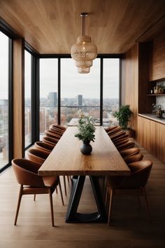 a dining room table with chairs and a vase on top of it in front of large windows