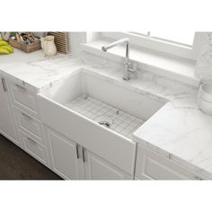 a white kitchen sink sitting under a window next to a counter top with a bowl on it