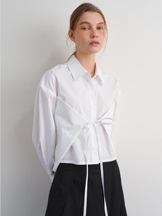 The Wrapped Shirt is a contemporary piece that effortlessly blends sophistication with casual charm. This product is designed with a unique wrap detail that accentuates the waist, creating a flattering silhouette. It is perfect for adding a stylish twist to both everyday and office wear. - This wrapped shirt features a versatile wrap-around tie, allowing for an adjustable and personalized fit.- The shirt is made from lightweight, breathable fabric, ensuring comfort throughout the day.- It includes a classic collar and button-down front, blending traditional elements with modern design.- A handmade Cali medal decoration has been attached to the lower right side of the front panel to add a unique point of interest. Chic Shirt With Tie Sleeves For Spring, Chic Shirt With Tie Sleeves For Workwear, Chic Cotton Shirt With Tie Sleeves, Chic Tie Waist Tops For Office, Chic Wrap Blouse With Tie Sleeves, Chic Wrap Top With Relaxed Fit, Chic Cotton Wrap Top For Spring, Chic Cotton Wrap Top, Versatile Workwear Tops With Tie Waist