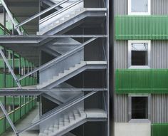 an image of stairs going up and down the side of a building with green shutters