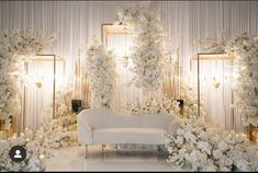 a white couch sitting in front of a wall covered with flowers and greenery next to two mirrors