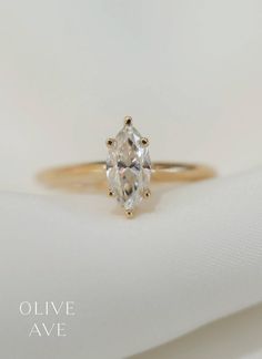 an oval cut diamond engagement ring on top of a white cloth with the words olive ave written below it