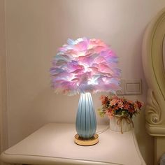 a blue vase filled with pink and purple flowers on top of a white table next to a mirror