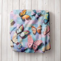 a blue and white checkered bag with colorful butterflies on the front, sitting on a wooden surface