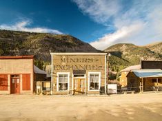 an old western town sits in the middle of nowhere, with mountains in the background