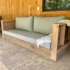 a couch sitting on top of a wooden floor next to a wall covered in wood planks