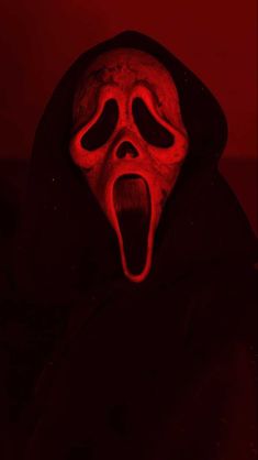 a person wearing a red mask with their mouth open and tongue out in the dark